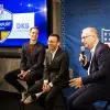 FootballR - NFL - Drei Männer in Anzügen sitzen auf einer Bühne bei einem NFL-Event in Frankfurt, Deutschland.