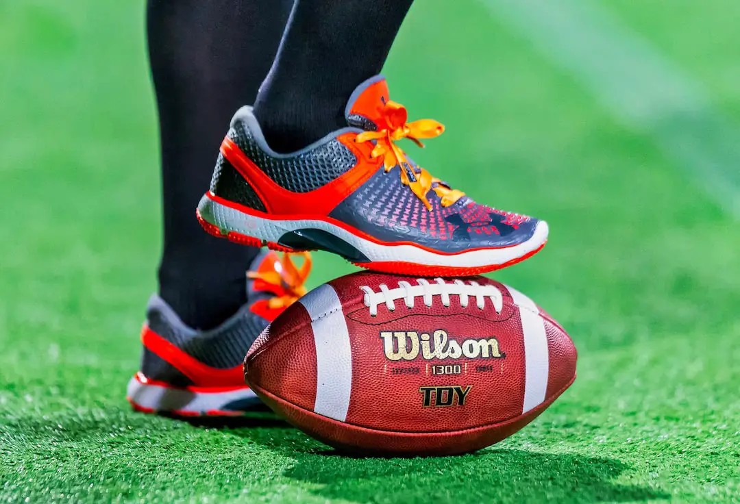 FootballR - NFL - Die Füße einer Person stehen auf einem Fußball.