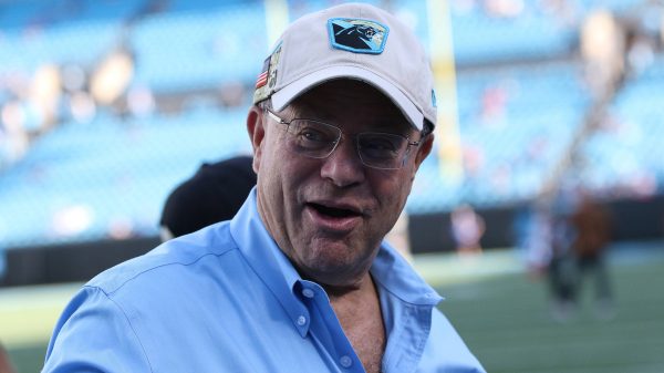 FootballR - NFL - David Tepper, der Besitzer der NFL Carolina Panthers, trägt ein blaues Hemd und eine Mütze und ist auf einem Footballfeld zu sehen.