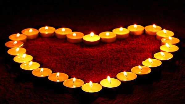 FootballR - NFL - Trauerfeier - Diese Beschreibung wurde automatisch generiert. Eine herzförmige Kerze mit brennenden Kerzen wird häufig bei Beerdigungen oder Gedenkfeiern zu Ehren eines Todesopfers verwendet.