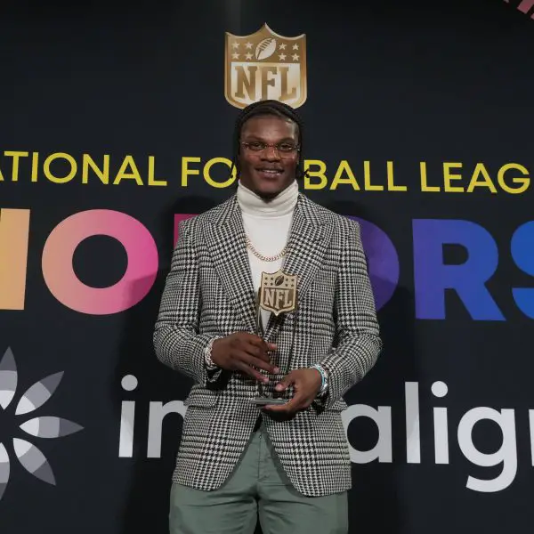 FootballR - NFL MVP Rennen 2024 - Diese Beschreibung wurde automatisch generiert. Lamar Jackson, der NFL MVP 2023, hält stolz seine Auszeichnung für seine bemerkenswerte Leistung in der National Football League.