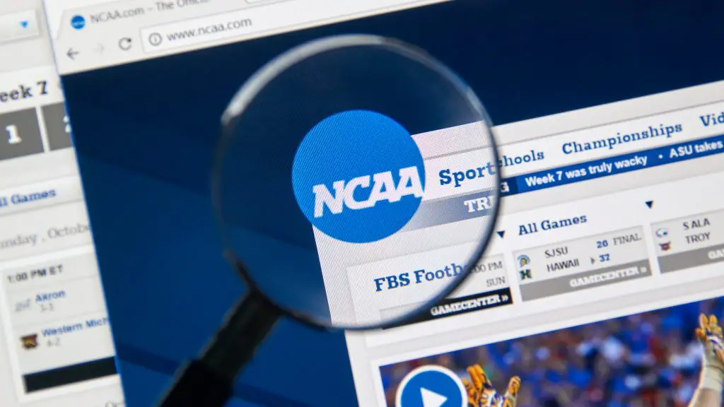 FootballR - NFL - Eine Lupe konzentriert sich auf das NCAA Logo, das auf einem Computerbildschirm angezeigt wird, und hebt in den Browser-Tabs verschiedene Abschnitte wie „Sport“, „Schulen“ und „Meisterschaften“ hervor. Unter dem Logo gibt es einen Zeitplan für Footballspiele und ein Video-Thumbnail mit einem Spieler in orange-weißer Uniform, was die umfangreichen Kommerzialisierungsbemühungen der NCAA hervorhebt. Diese Beschreibung wurde automatisch generiert.